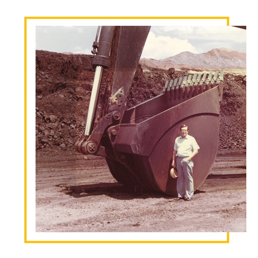 Mr. Wright Found of ASCO standing beside an excavator bucket.