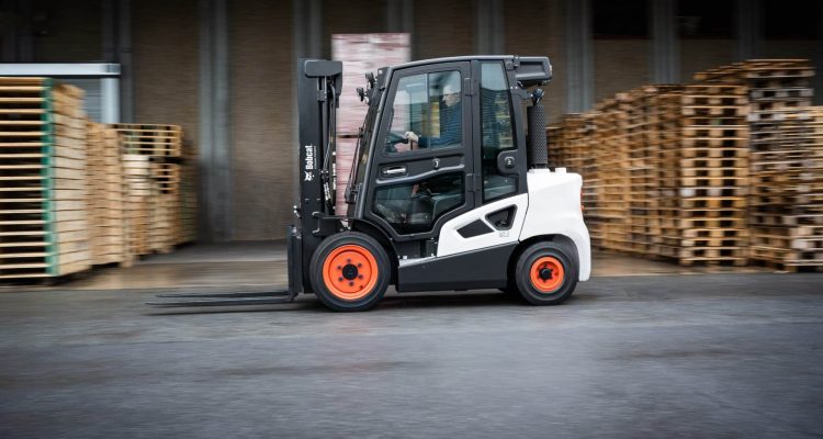 A Black And White Bobcat Forklift Moving Pallets In An Industrial Warehouse Setting.