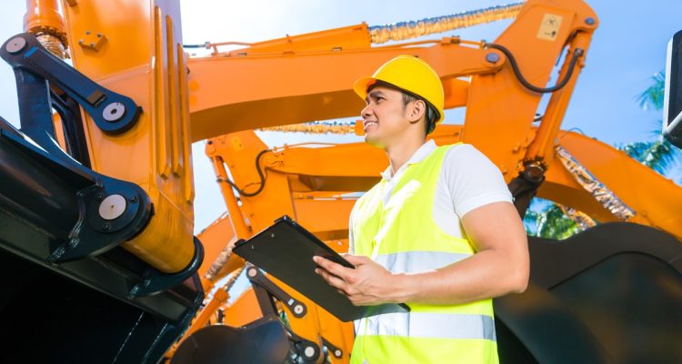 A Construction Worker In A Neon Vest And Yellow Hard Hat Holding A Clipboard During A Construction Site Safety Inspection.